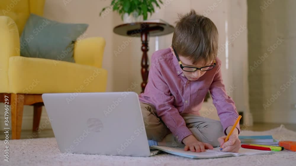 concentrated boy student using laptop at home writing in book busy with distant education. Spbas child learning from home during quarantine. internet, smart, social distancing concept. concentrated boy student using laptop at home writing in book busy with distant education. Spbas child learning from home during quarantine. internet, smart, social distancing concept.