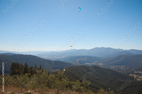 View of rolling hills with skydivers in view on bright sunny day