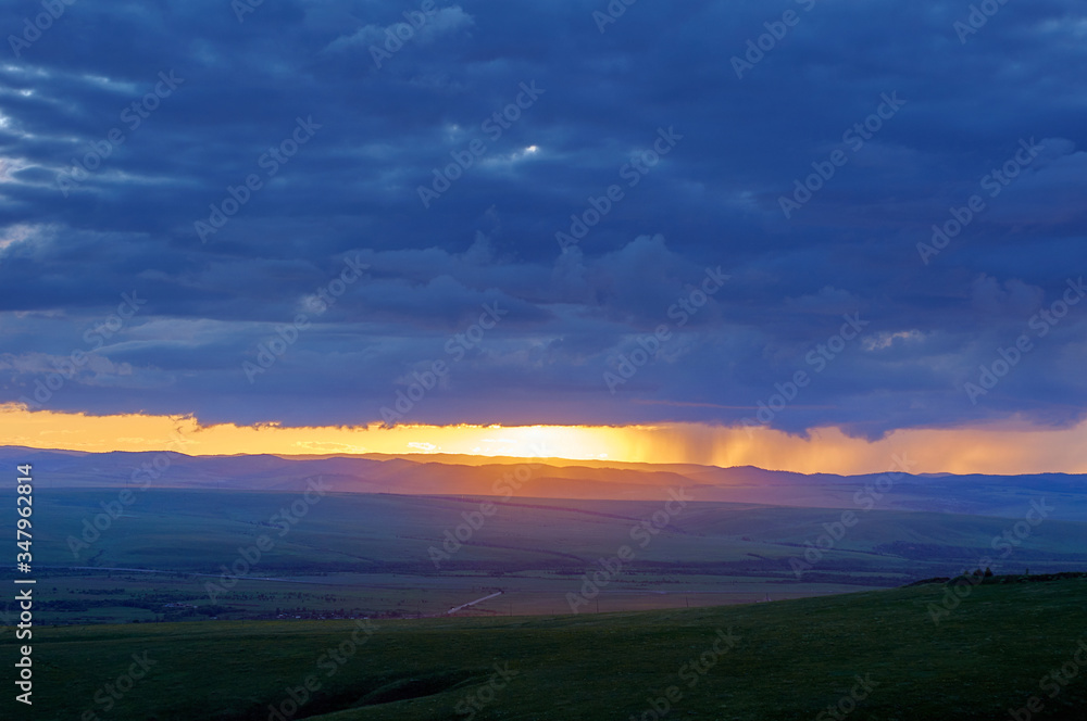 Rain clouds over distant hills at sunset. Zabaykalsky Krai. Russia.