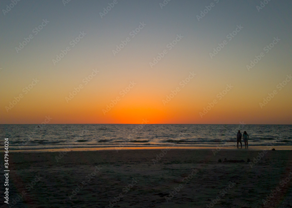 Man And Woman Standing At Beach Against Sky During Sunset