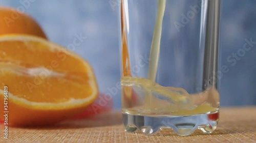 Orange juice is poured into a transparent glass with a slow motion close-up