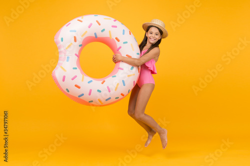 Summer swimsuit. summer water activities. active and energetic vacation. ready for playing and sunbathing. Surfing in the sea. little girl and rubber ring. jumping kid in swimwear at swimming pool