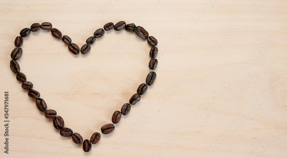 The shape of the heart is laid out on a light background of roasted coffee beans, there is room for text. The shape of the heart is laid out on a light background of roasted coffee beans, there is room for text.