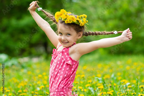 Girl 5 y.o. playing in the meadow with dandelions
