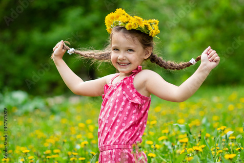 Girl 5 y.o. playing in the meadow with dandelions