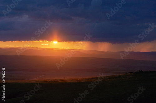 Rain over the distant hills at sunset. © Anna