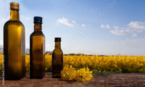 Rapeseed oil (rapeseed) and rapeseed flowers on a wooden board.