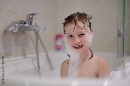 Fényképezés little girl in bath playing with soap foam