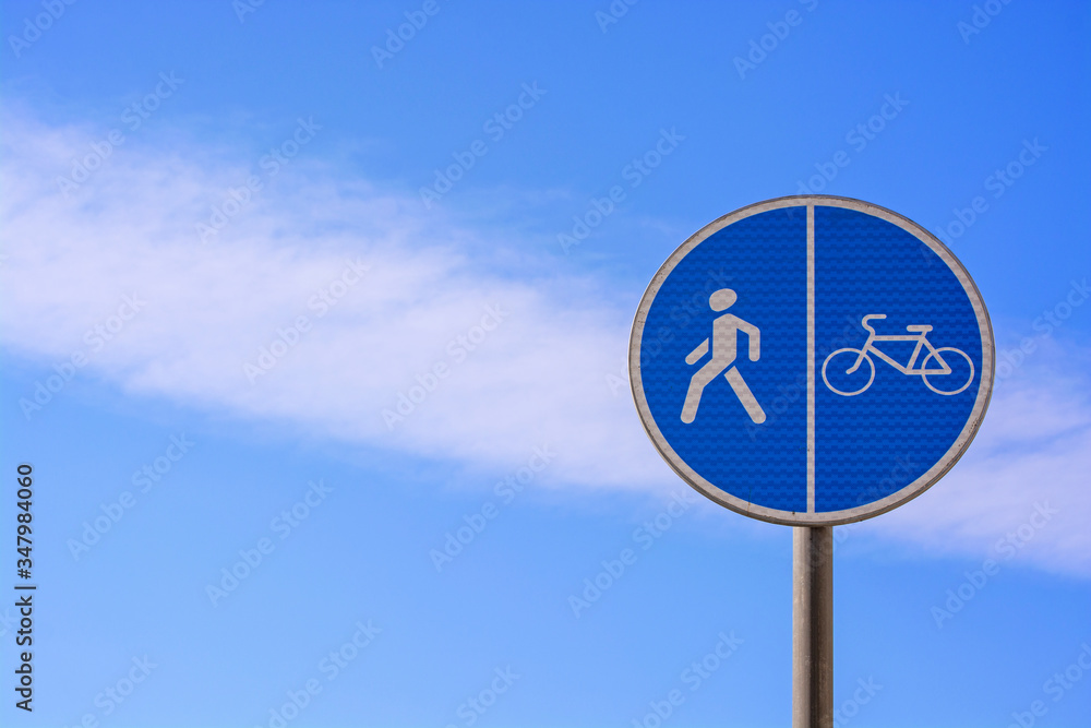 Round blue sign Pedestrian and bicycle path with combined path on the background of a beautiful cloudy sky
