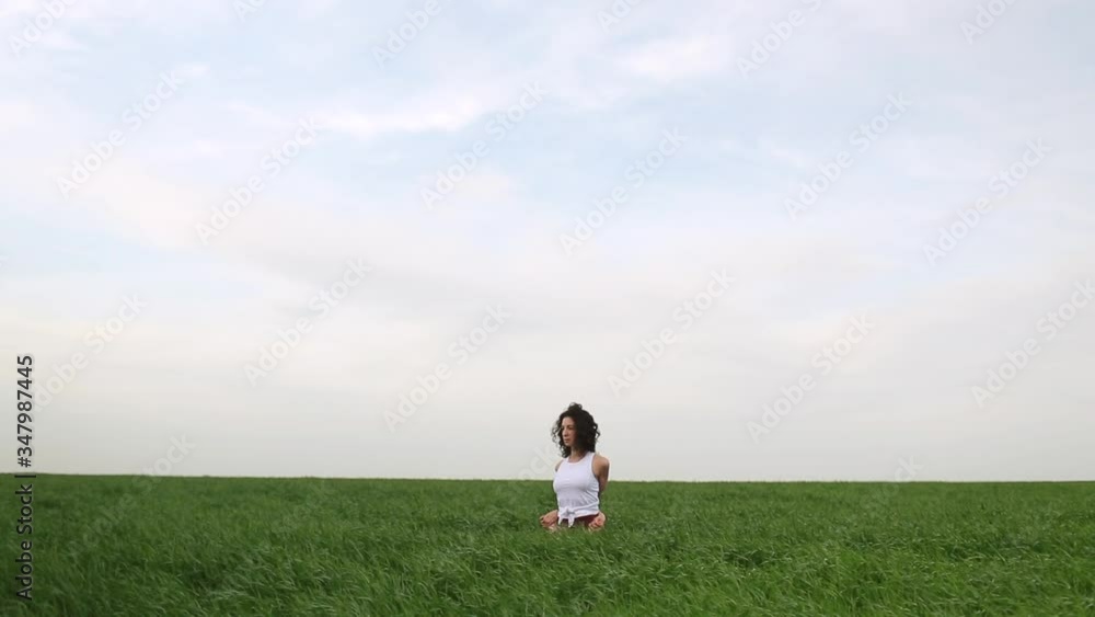 Young slim girl doing yoga outdoors in a green field Young slim girl doing yoga outdoors in a green field