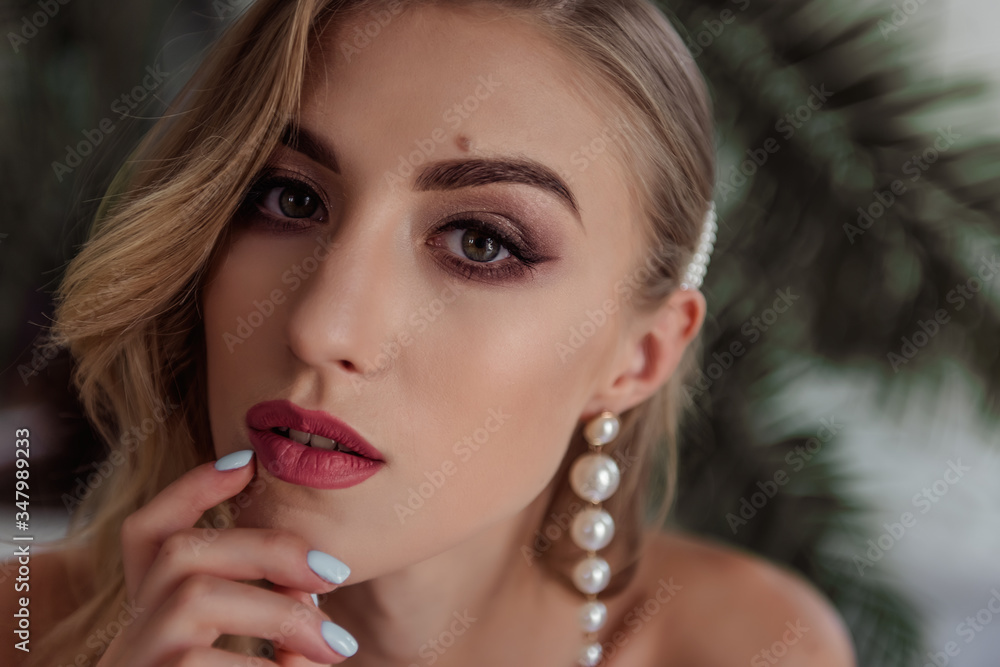 A beautiful girl with natural, beautiful, professional makeup and a fancy fashion fashion cut in her hair and long white pearl earrings. hands near the face, a large portrait. selective focus A beautiful girl with natural, beautiful, professional makeup and a fancy fashion fashion cut in her hair and long white pearl earrings. hands near the face, a large portrait. selective focus