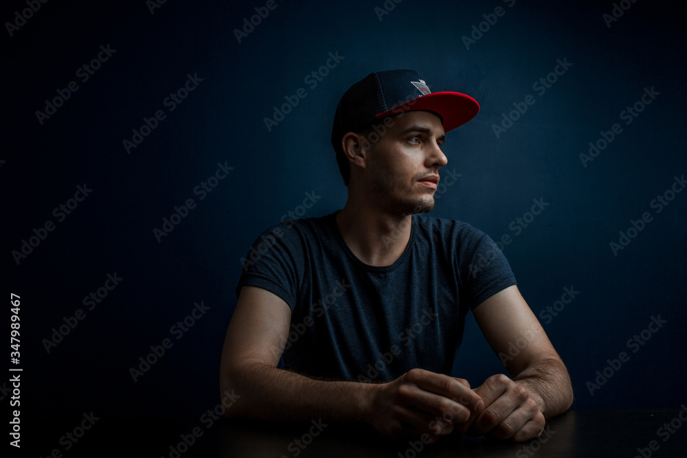 focused guy in a cap looks aside and his hands on the table focused guy in a cap looks aside and his hands on the table