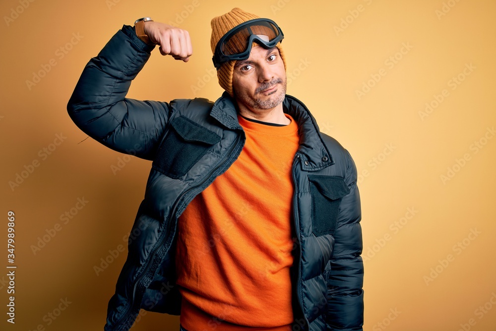 Young handsome skier man skiing wearing snow sportswear using ski goggles Strong person showing arm muscle, confident and proud of power Young handsome skier man skiing wearing snow sportswear using ski goggles Strong person showing arm muscle, confident and proud of power