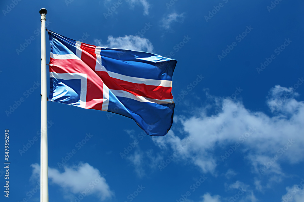 Flag of Iceland on a high flagpole. Waving Icelandic Flag Against a Blue Sky with Clouds. National Flag of Iceland. Image for Icelandic Republic Day, National Day