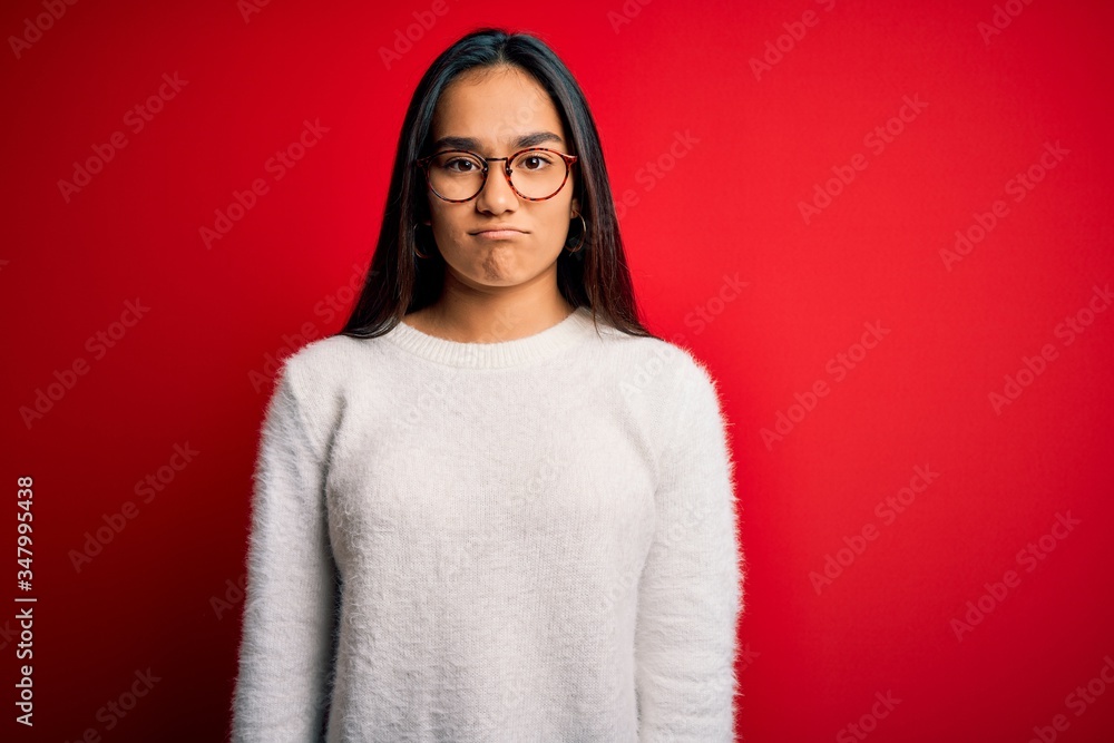 Young beautiful asian woman wearing casual sweater and glasses over red background depressed and worry for distress, crying angry and afraid. Sad expression. Young beautiful asian woman wearing casual sweater and glasses over red background depressed and worry for distress, crying angry and afraid. Sad expression.