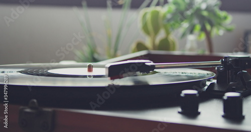 Vintage portable record player playing vynil record on blurred background. Selective focus, macro.