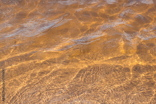 Golden sand of the beach under clear water of sea