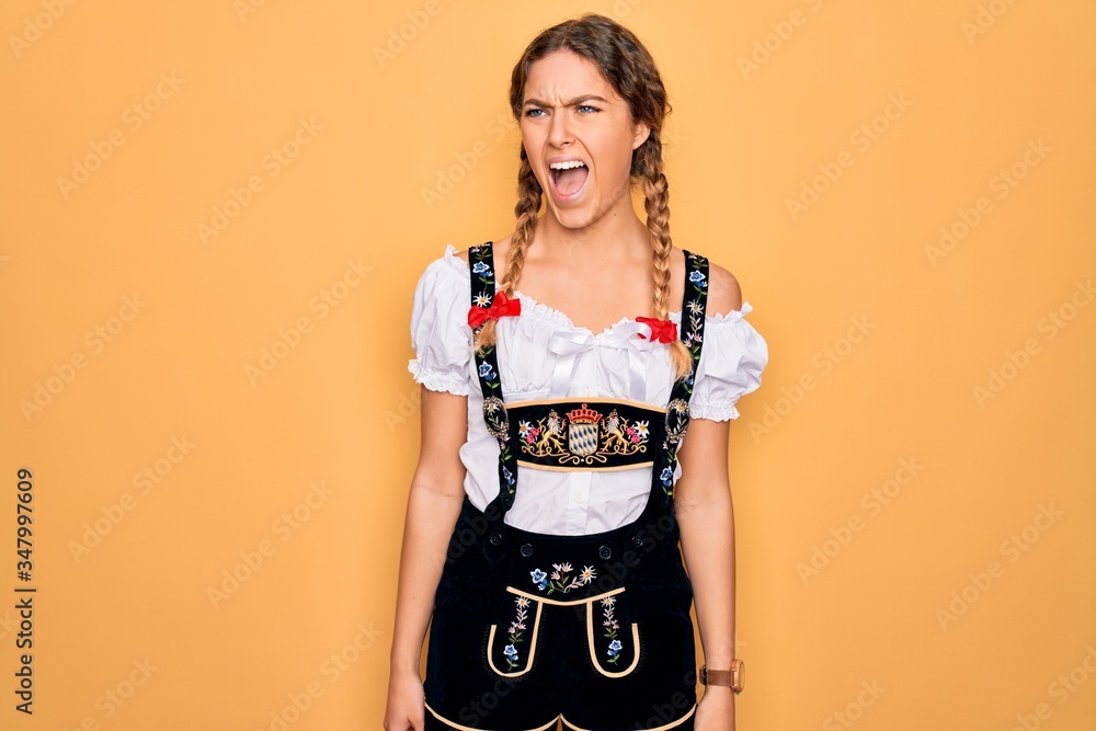 Young beautiful blonde german woman with blue eyes wearing traditional octoberfest dress angry and mad screaming frustrated and furious, shouting with anger. Rage and aggressive concept. Young beautiful blonde german woman with blue eyes wearing traditional octoberfest dress angry and mad screaming frustrated and furious, shouting with anger. Rage and aggressive concept.