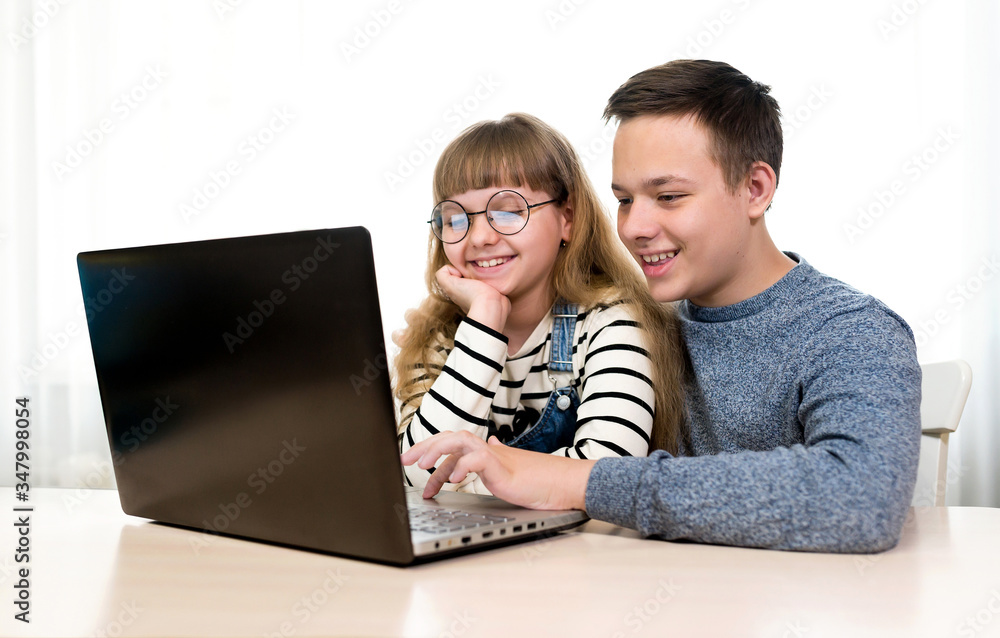 Happy children with a laptop. Remote communication on the Internet, online education. Family, children, technology and home concept Happy children with a laptop. Remote communication on the Internet, online education. Family, children, technology and home concept