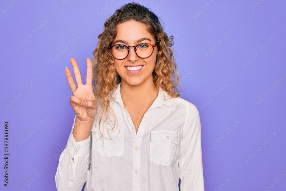 Young beautiful woman with blue eyes wearing casual shirt and glasses over purple background showing and pointing up with fingers number three while smiling confident and happy. Young beautiful woman with blue eyes wearing casual shirt and glasses over purple background showing and pointing up with fingers number three while smiling confident and happy.