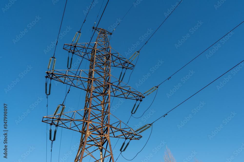 Metal pole with power lines wires against the blue sky. Metal pole with power lines wires against the blue sky.