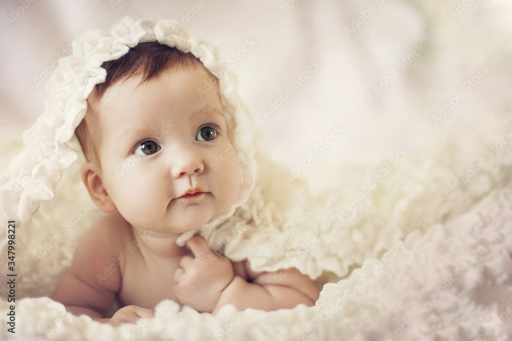 Happy young baby lying on tummy on a light bedspread. Happy young baby lying on tummy on a light bedspread.