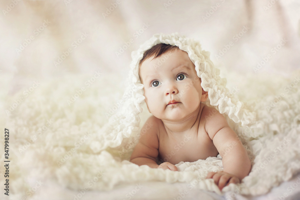 Happy young baby lying on tummy on a light bedspread. Happy young baby lying on tummy on a light bedspread.