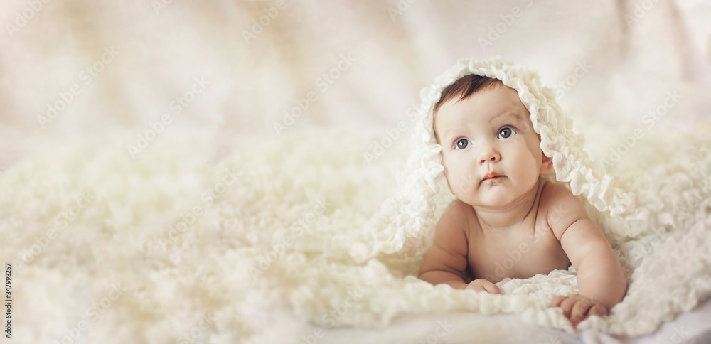 Happy young baby lying on tummy on a light bedspread. Happy young baby lying on tummy on a light bedspread.