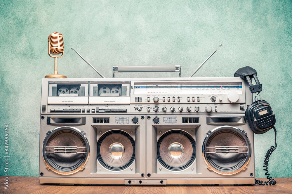 Foto Stock Retro old ghetto blaster stereo radio cassette tape recorder  boombox from circa 80s, golden microphone, headphones front concrete wall  background. Nostalgic music concept. Vintage style filtered photo | Adobe  Stock