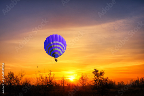 Blue hot air balloon on the background of bright red sunset.