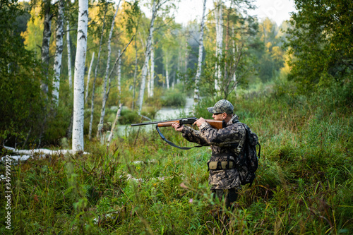 Hunter aiming with weapon at the outdoor hunting