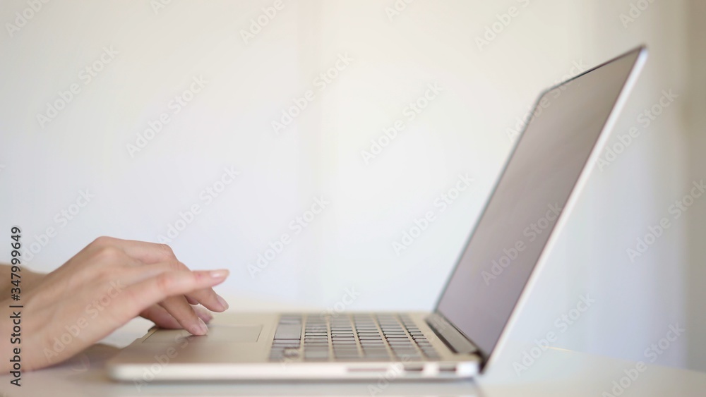Close up hands working with laptop in white home office. Close up hands working with laptop in white home office.
