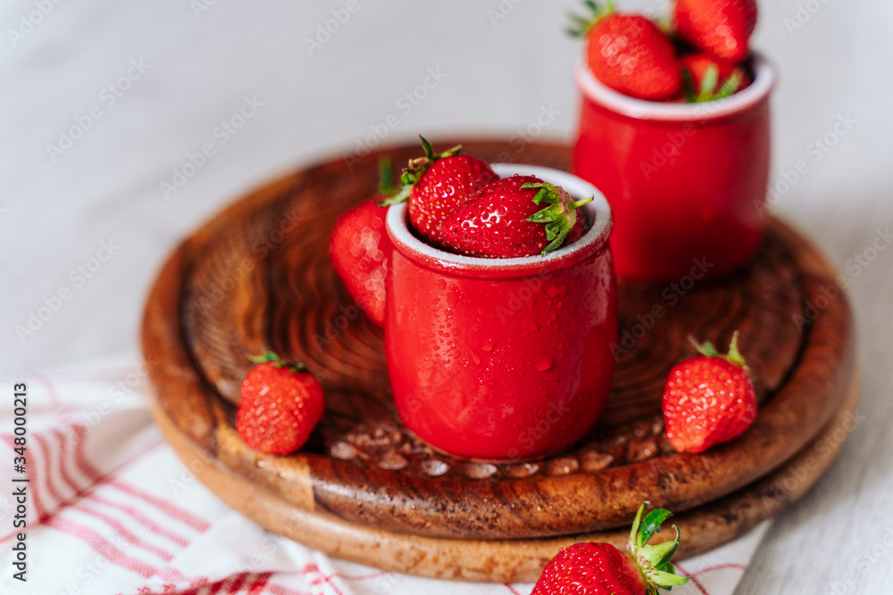 fresh strawberries in red pots on a wooden background, on a drop of water berries. healthy nutrition, vitamin charge, summer berries fresh strawberries in red pots on a wooden background, on a drop of water berries. healthy nutrition, vitamin charge, summer berries