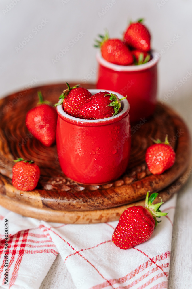 fresh strawberries in red pots on a wooden background, on a drop of water berries. healthy nutrition, vitamin charge, summer berries fresh strawberries in red pots on a wooden background, on a drop of water berries. healthy nutrition, vitamin charge, summer berries