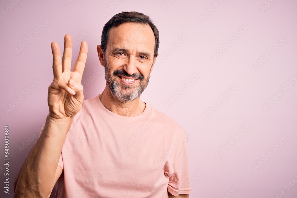 Middle age hoary man wearing casual t-shirt standing over isolated pink background showing and pointing up with fingers number three while smiling confident and happy. Middle age hoary man wearing casual t-shirt standing over isolated pink background showing and pointing up with fingers number three while smiling confident and happy.