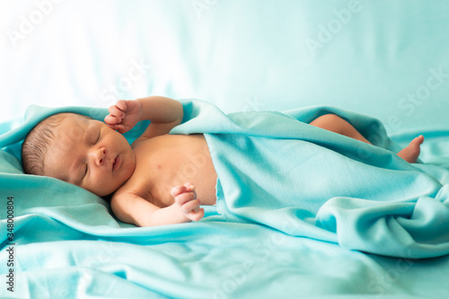 Obraz na płótnie Little newborn baby resting on soft, delicate fabric of blue blanket. Baby falling asleep covered with blanket. w salonie