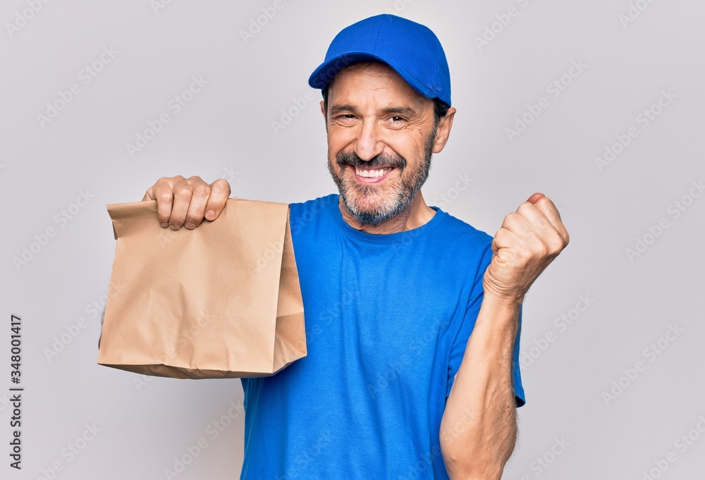 Middle age handsome delivery man wearing cap holding paper bag with takeaway food screaming proud, celebrating victory and success very excited with raised arm Middle age handsome delivery man wearing cap holding paper bag with takeaway food screaming proud, celebrating victory and success very excited with raised arm