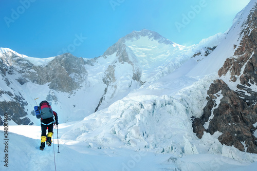 Mountaineer with backpack crossing Khumbu glacier crevasse during ascent on Everest