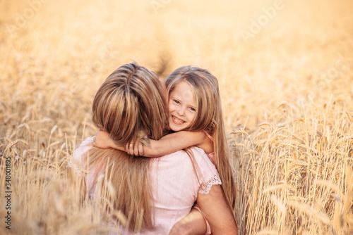 Cheerful daughter and mother having fun in wheat field, happy time together