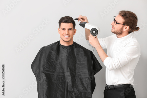Young hairdresser working with client against white background