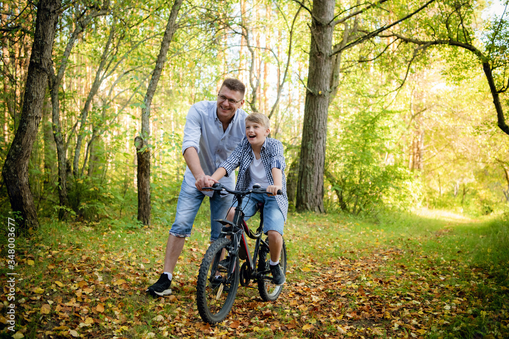 young father teaching his smiling son how to ride a bike