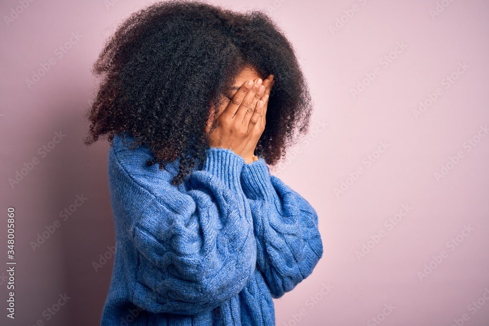 Young beautiful african american woman with afro hair wearing winter sweater over pink background with sad expression covering face with hands while crying. Depression concept. Young beautiful african american woman with afro hair wearing winter sweater over pink background with sad expression covering face with hands while crying. Depression concept.