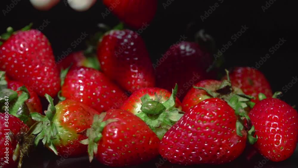 Group fresh strawberries in neon lighting: a latex glove picks up and leaves fresh strawberry Group fresh strawberries in neon lighting: a latex glove picks up and leaves fresh strawberry