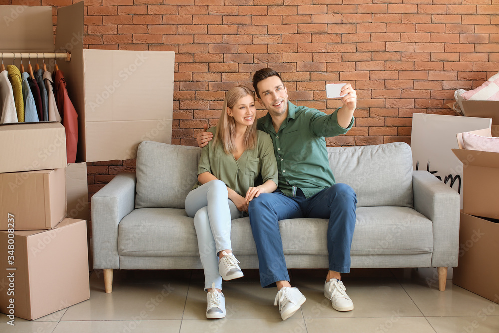 Obraz premium Young couple taking selfie in their new flat on moving day