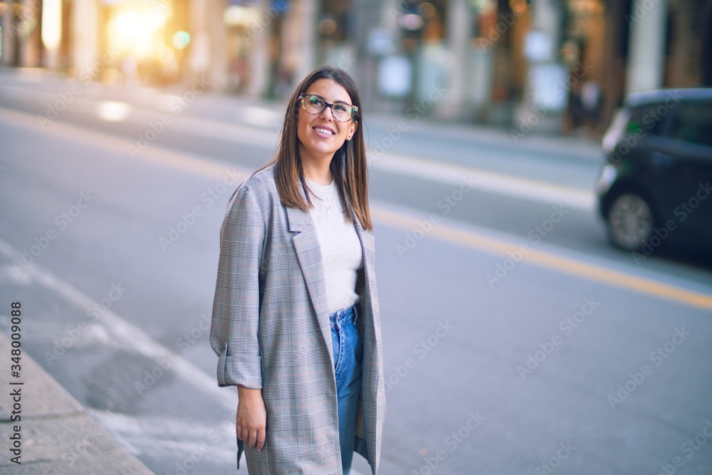 Fototapeta premium Young beautiful woman smiling happy and confident. Standing with smile on face at the town street