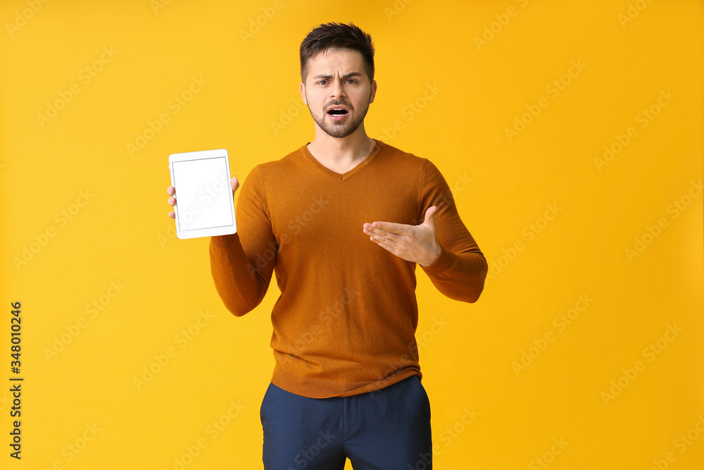 Displeased young man with tablet computer on color background Displeased young man with tablet computer on color background