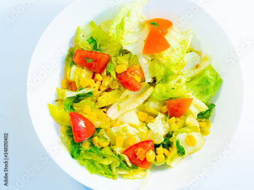 Green vegan salad from green leaves mix and vegetables. Top view on gray stone table.fresh salad in a white plate.Tasty vegetable salad in bowl on white background