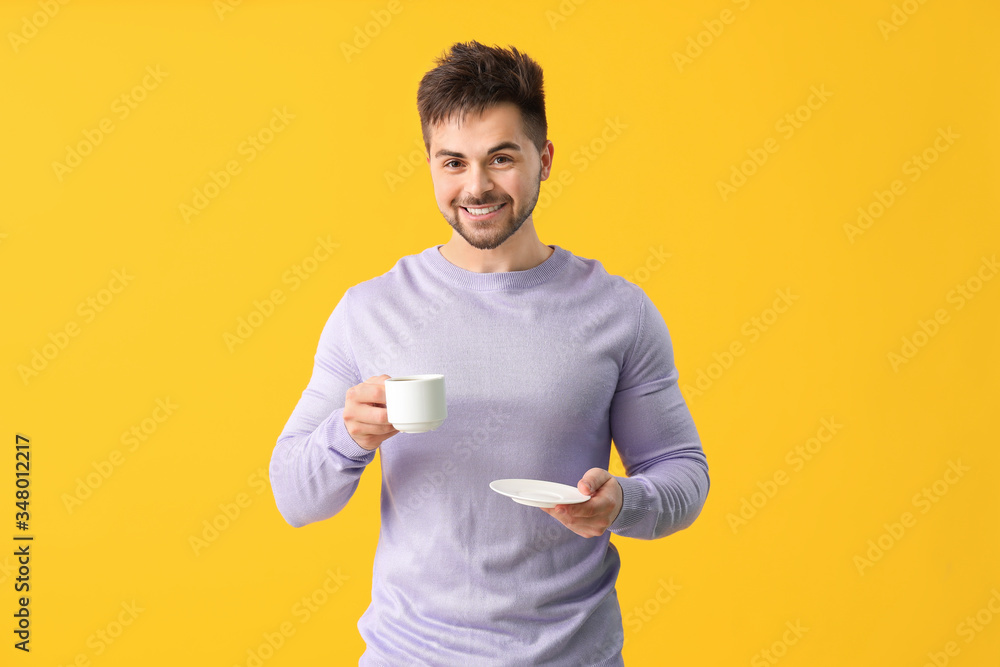 Young man with cup of hot coffee on color background Young man with cup of hot coffee on color background