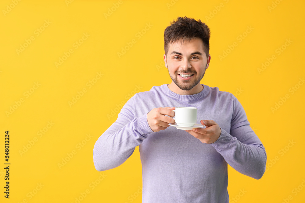 Young man with cup of hot coffee on color background Young man with cup of hot coffee on color background