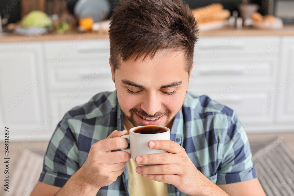 Young man drinking hot coffee in kitchen Young man drinking hot coffee in kitchen